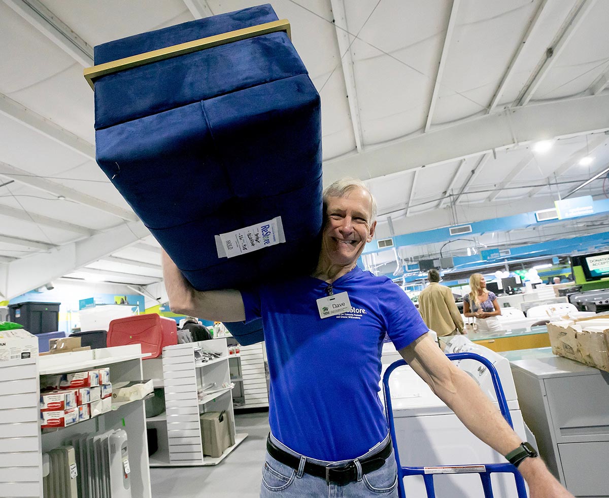 Worker at Yorktown ReStore grand-opening carrying furniture