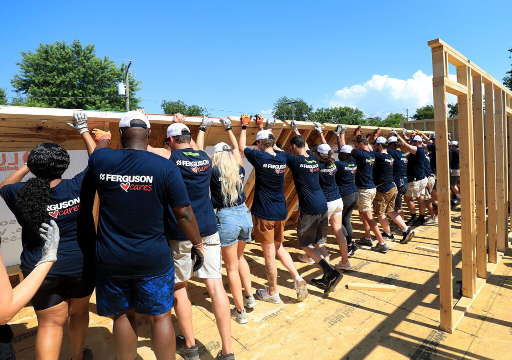 Entire Ferguson team raises a wall on Habitat construction site.