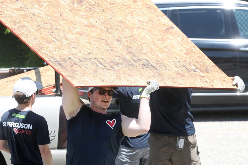 Ferguson volunteer lifting wood panel during Habitat build.