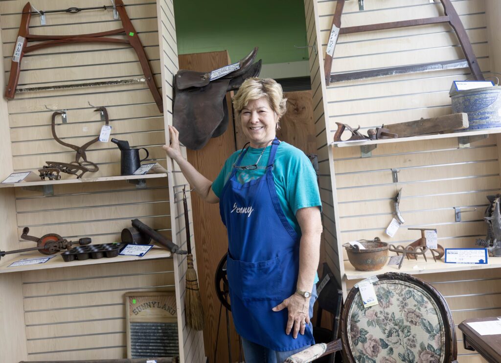 nny McCauley stands beside a curated display of antiques at the Habitat ReStore.