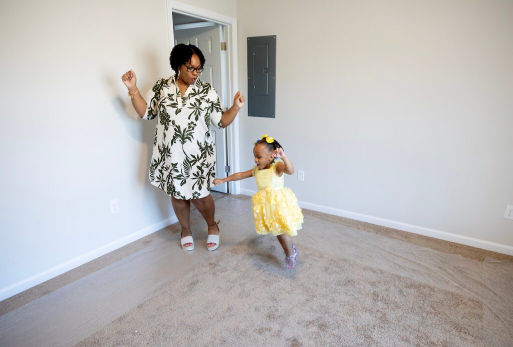 Kendra and her daughter dancing in an empty room of their new Habitat for Humanity home.