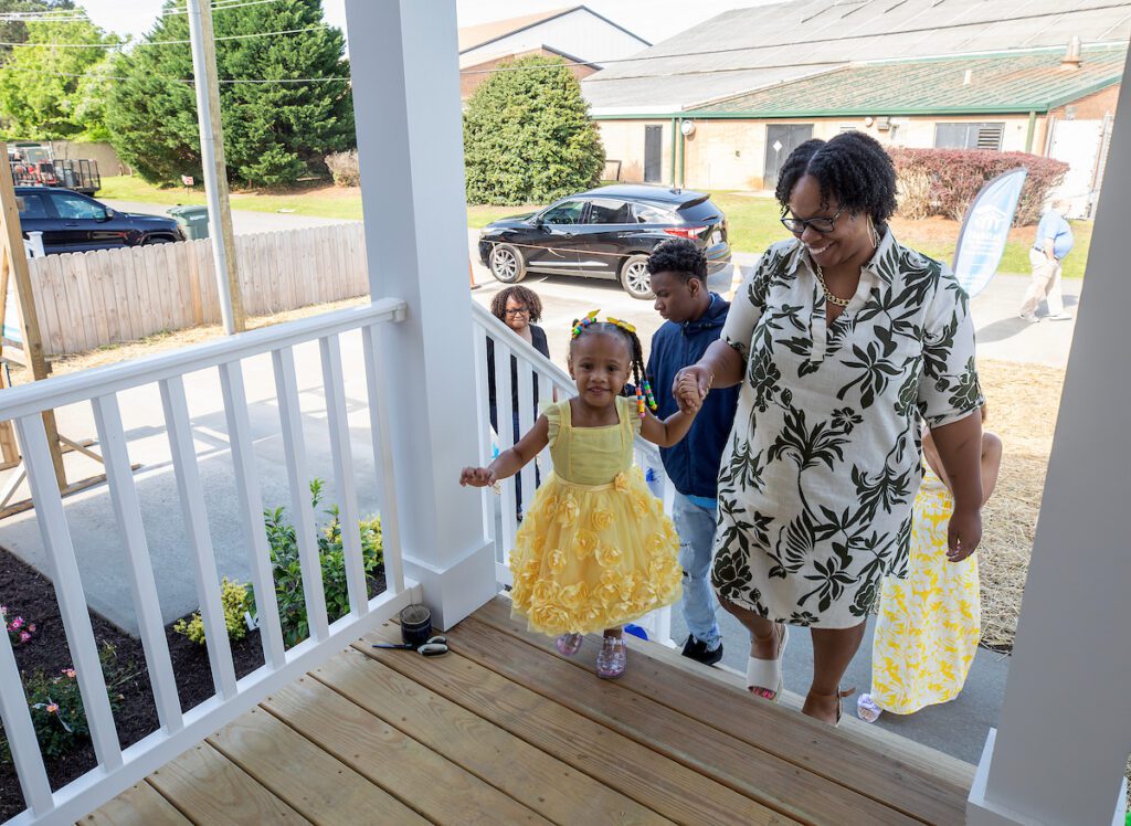 Kendra and her children walking up the front steps of their new Habitat for Humanity home.
