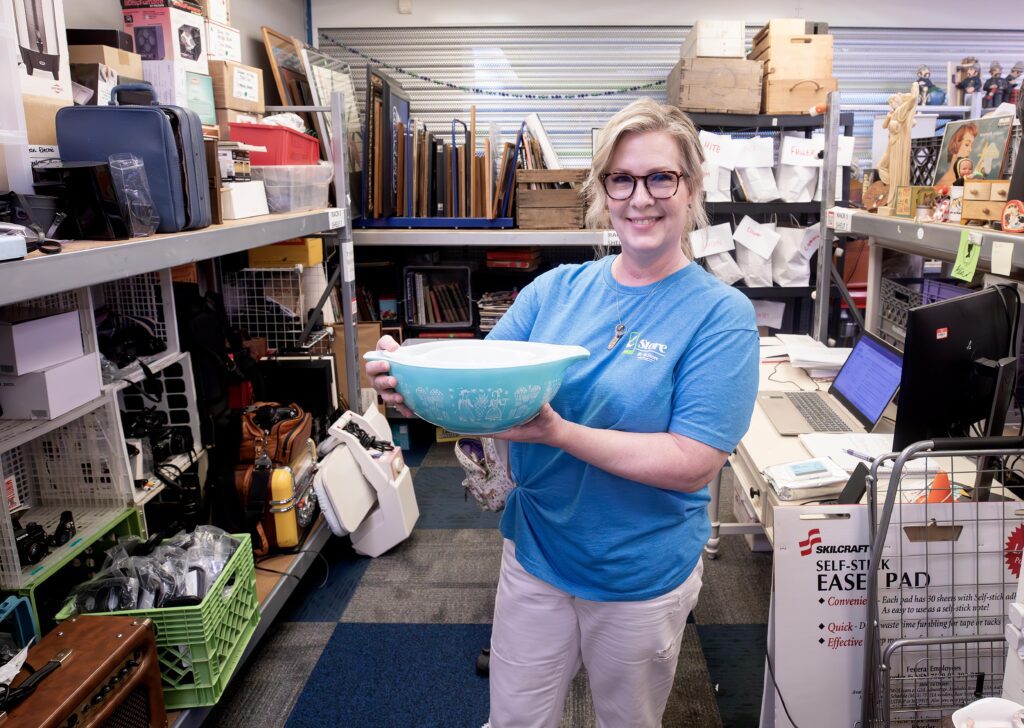 Nancy holding a turquoise Pyrex mixing bowl in ReStore.