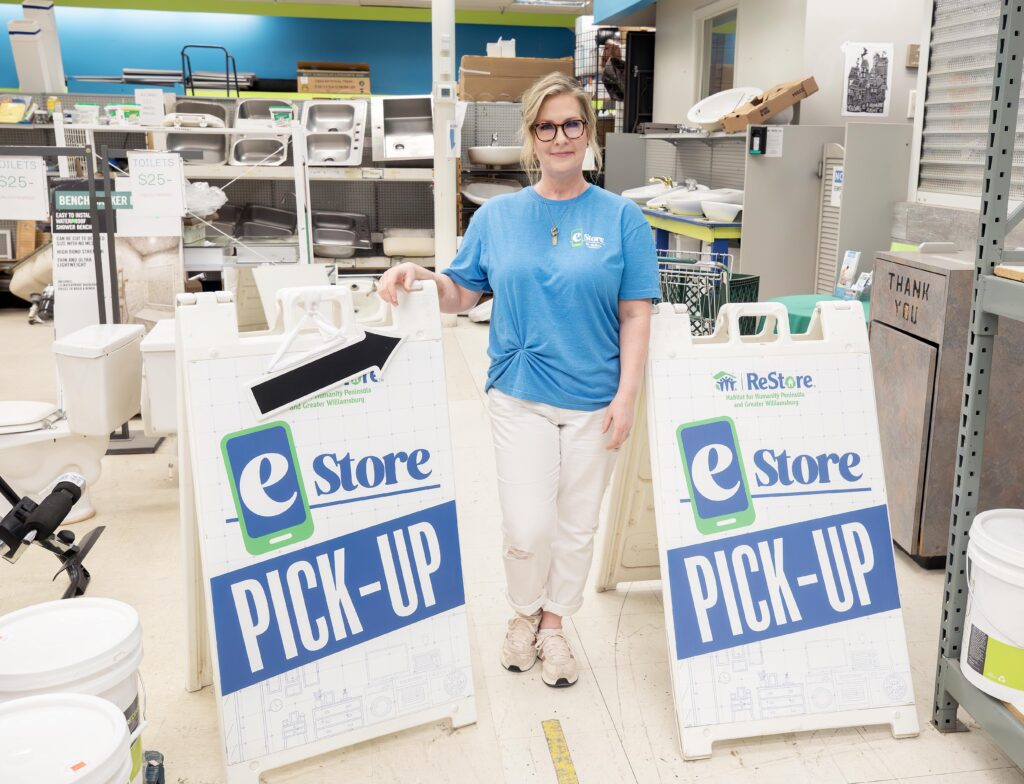 Nancy standing next to Habitat ReStore eStore pick-up signs.