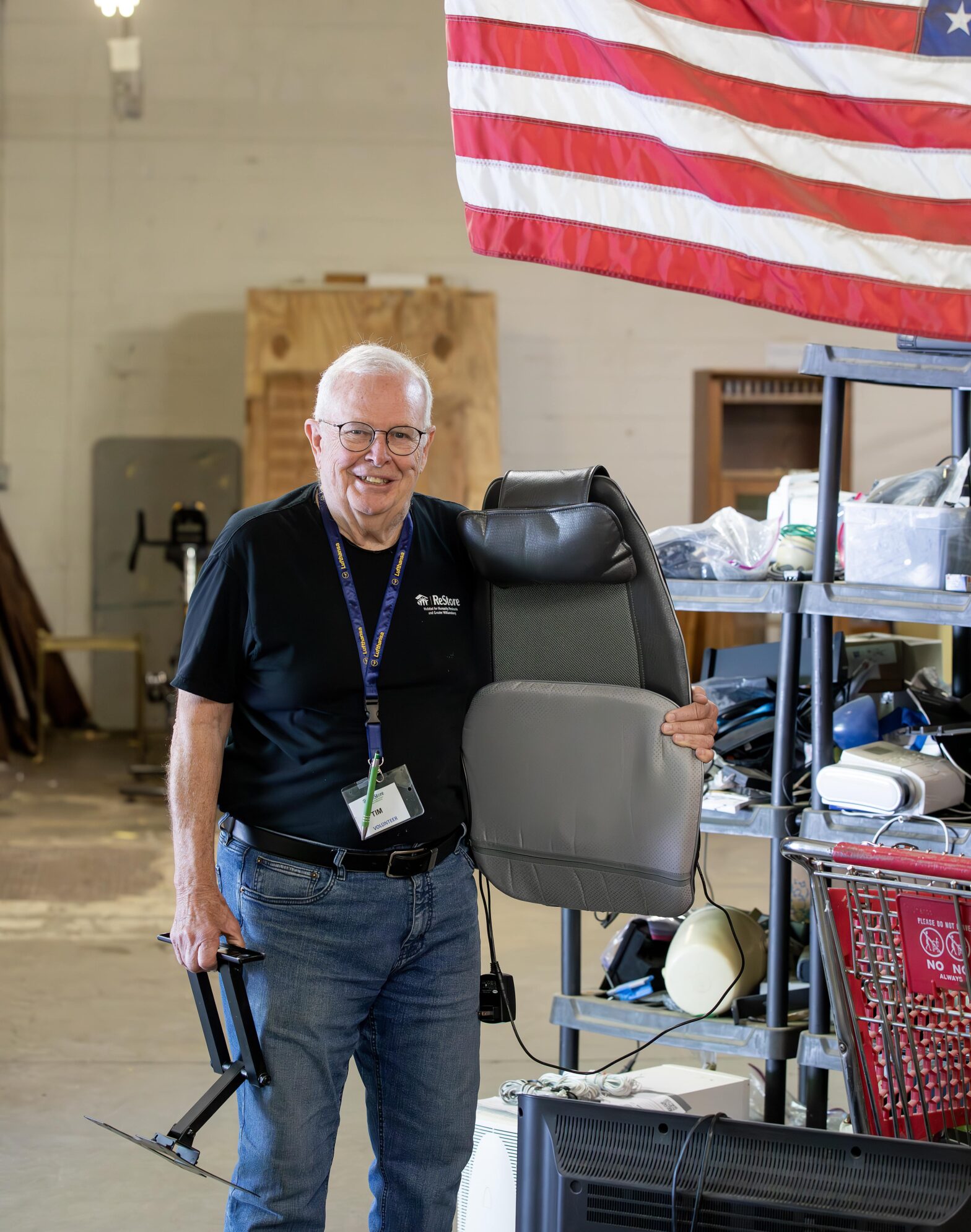 Tim McSwain sorts electronics donations under an American flag at Williamsburg ReStore.
