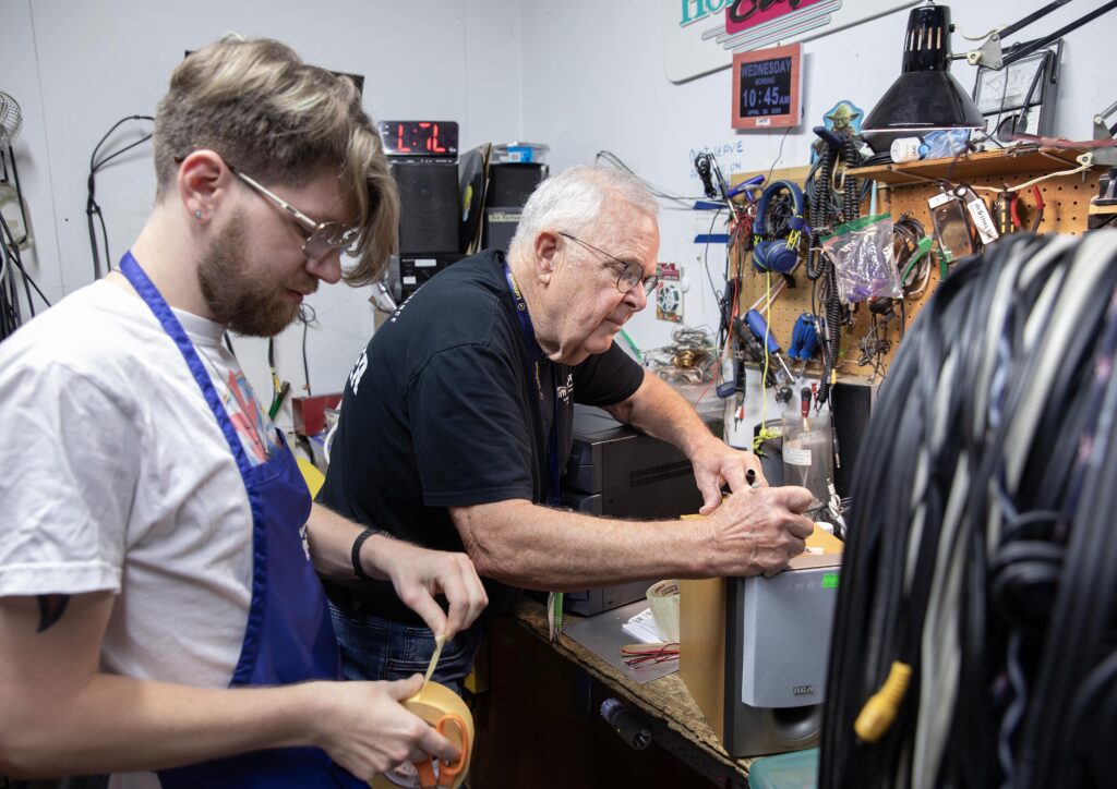 Volunteers working side by side on electronics repair.