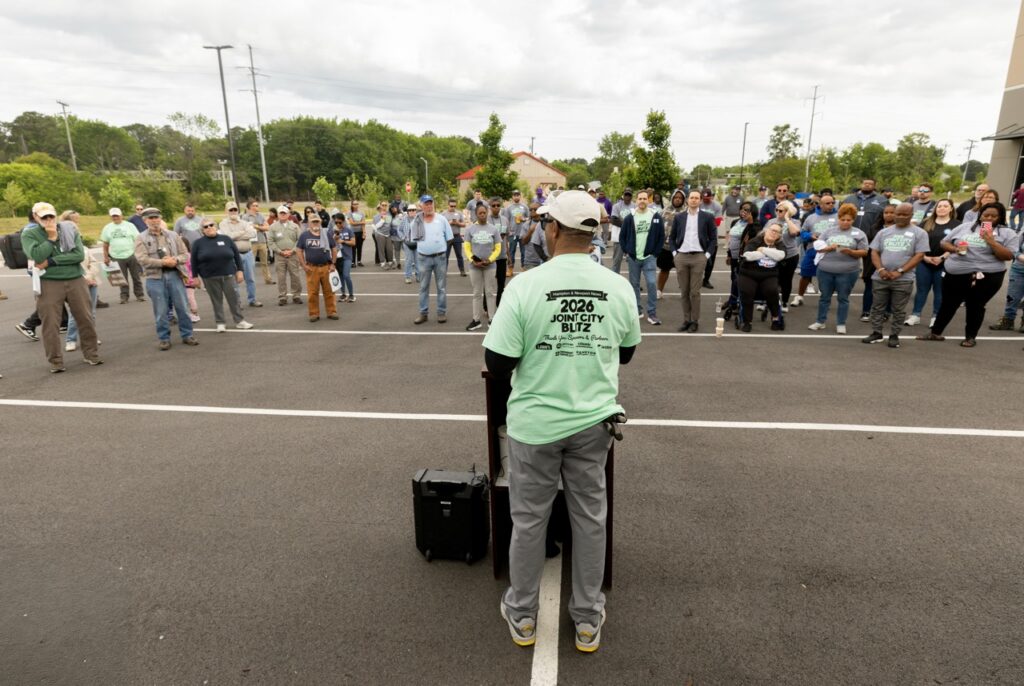 Man addressing a crowd of people in a parking lot