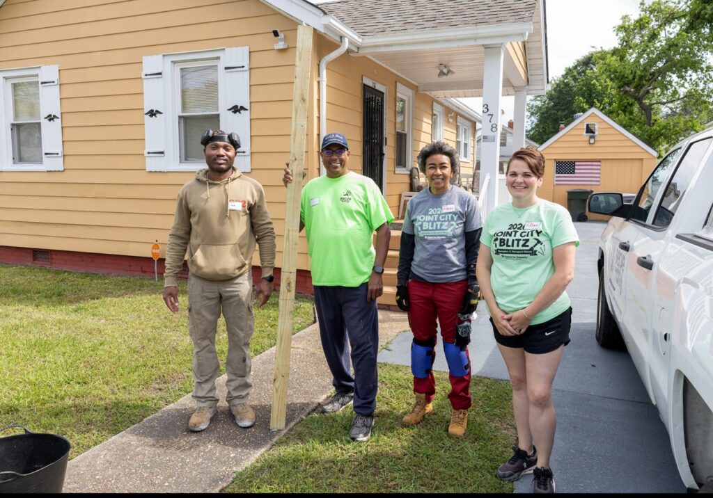 Group of people posing for a photo outside a Habitat for Humanity Home Repair Blitz site