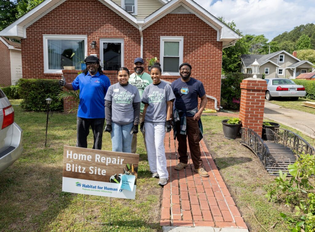 Group of people posing for a photo outside a Habitat for Humanity Home Repair Blitz site