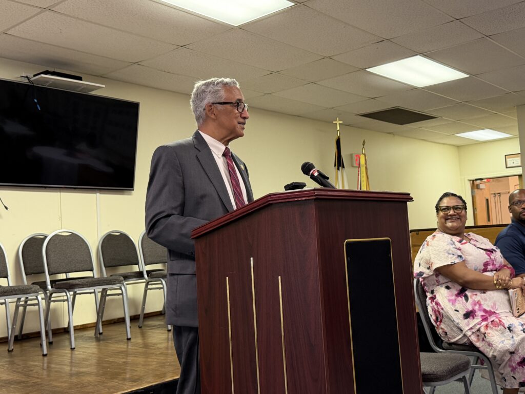Congressman Bobby Scott speaking at a podium, addressing an audience of engaged listeners in a conference setting.