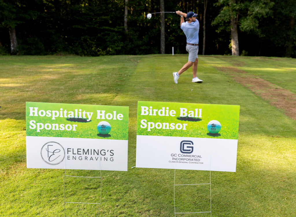 A golfer swings on a course near sponsor signs for Fleming’s Engraving and GC Commercial Incorporated.